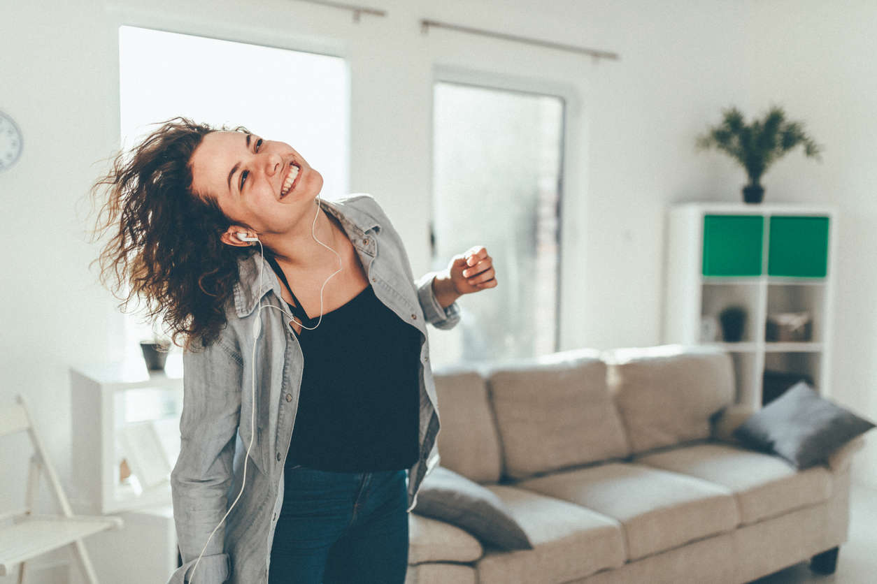 a woman dancing in the living room with headphones on