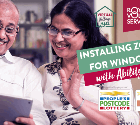 an older couple wearing glasses sat on a sofa and waving at an ipad