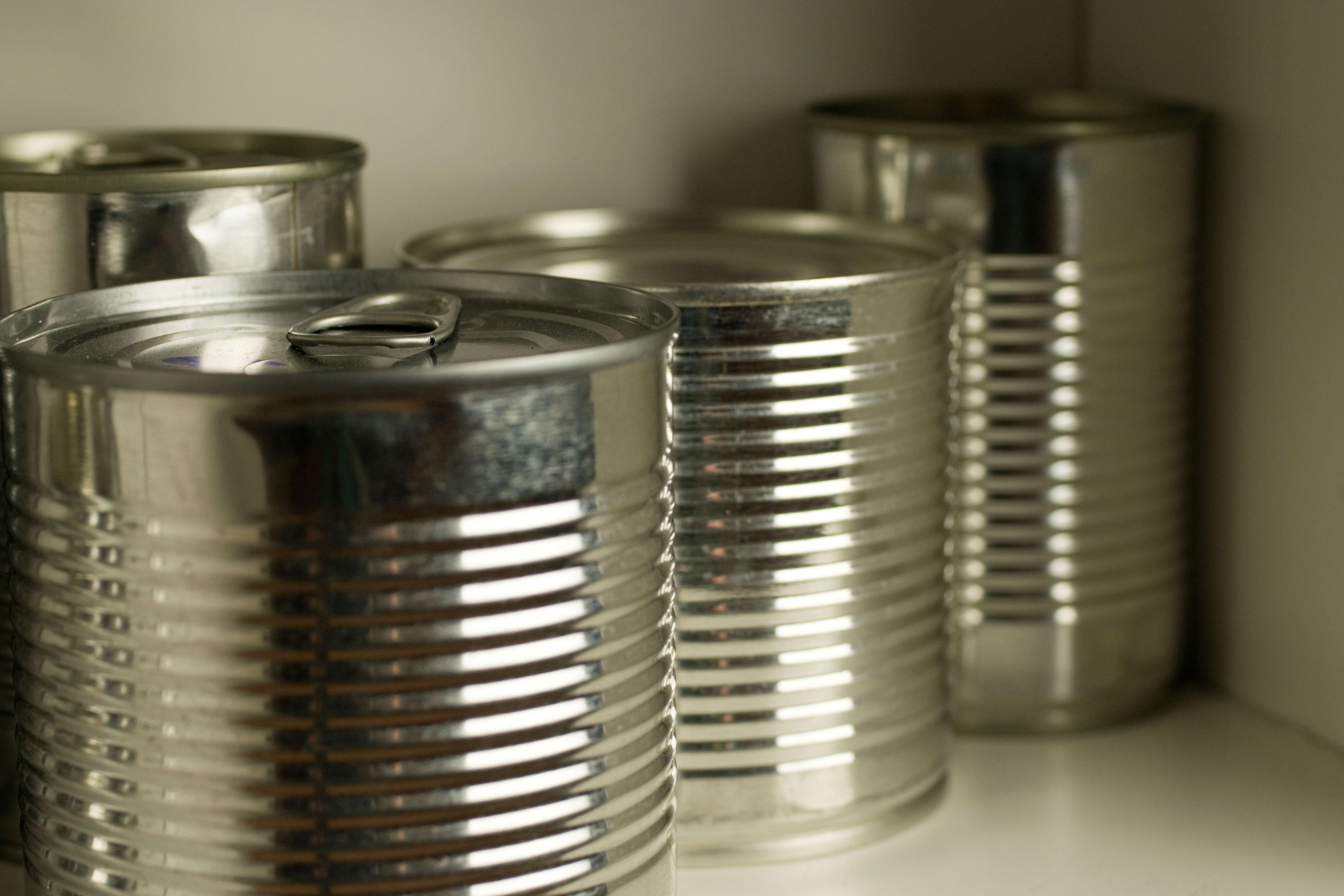 a close up of unbranded silver tin cans in a cupboard