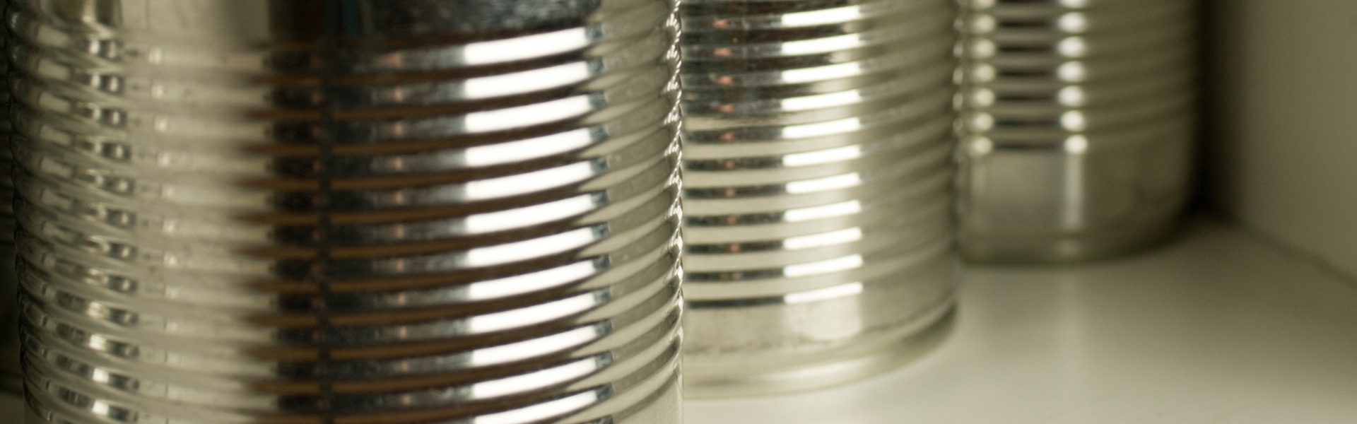 a close up of unbranded silver tin cans in a cupboard