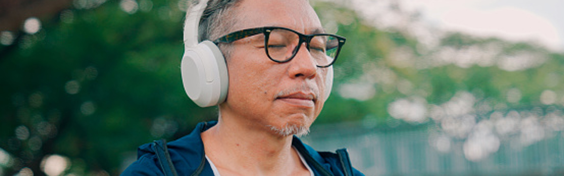 a man wearing white overhead headphones with his eyes closed outside