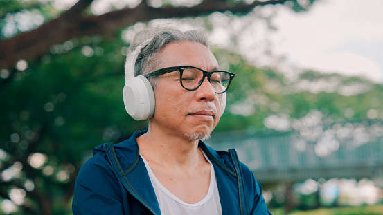 a man wearing white overhead headphones with his eyes closed outside