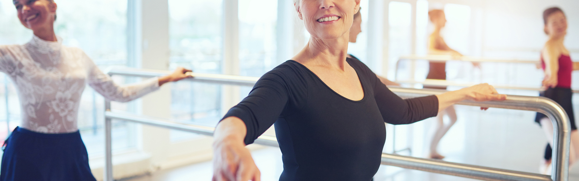 a woman in a black top at a barre taking part in a ballet class