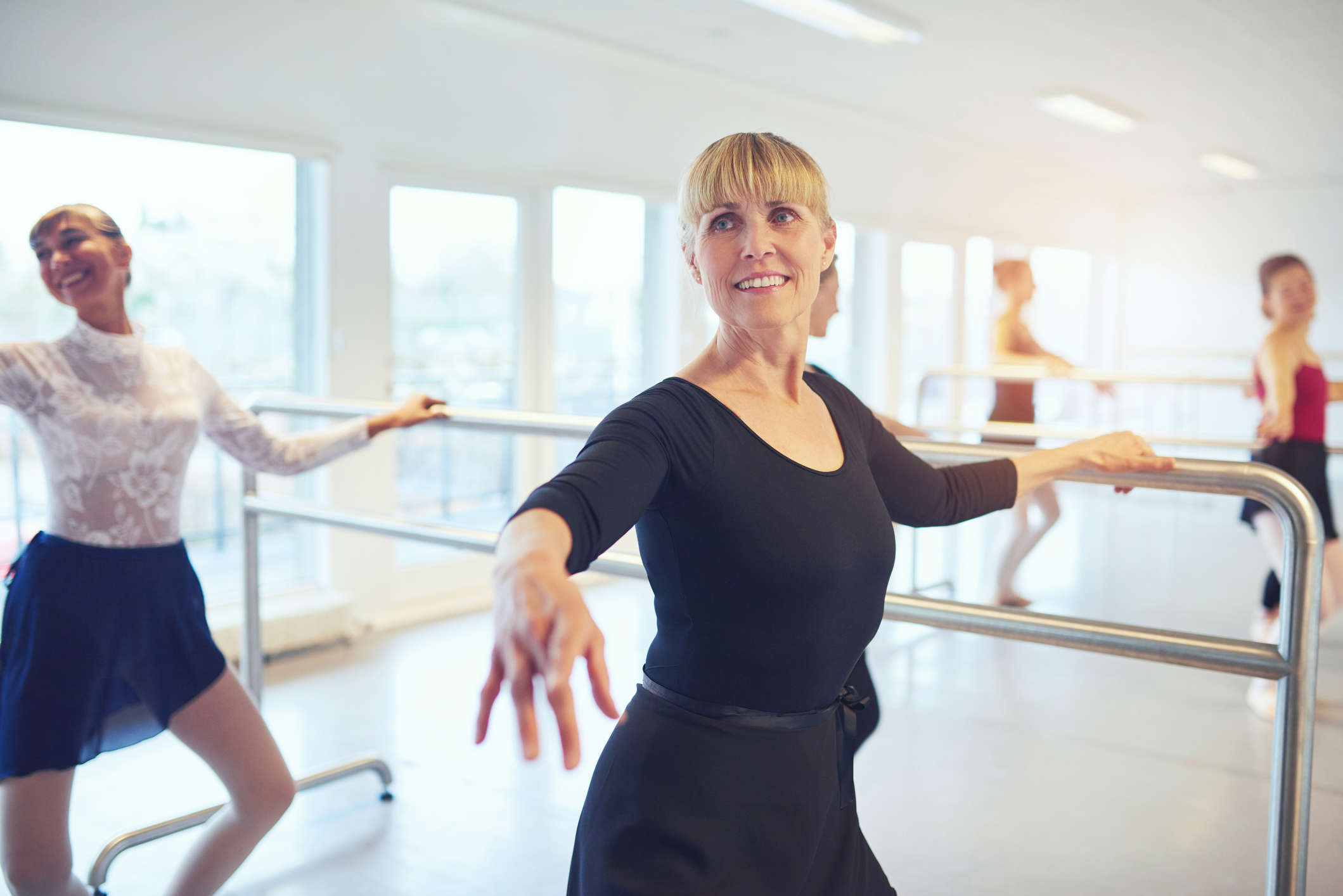 a woman in a black top at a barre taking part in a ballet class