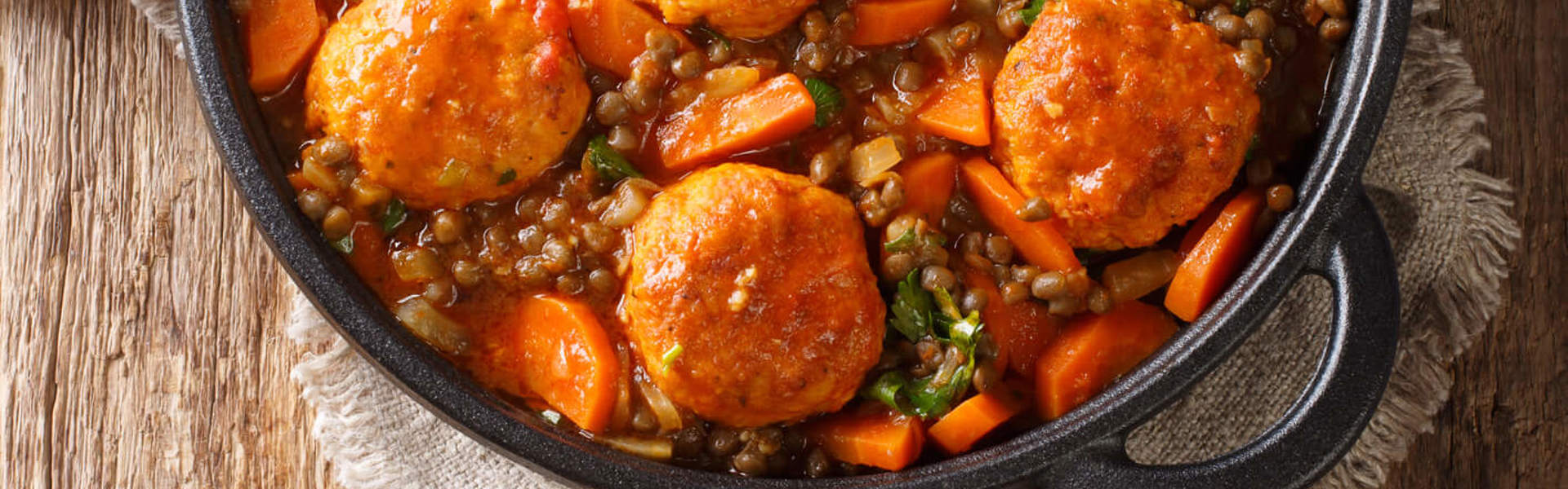 a homemade casserole in a black cooking pot on a wooden background