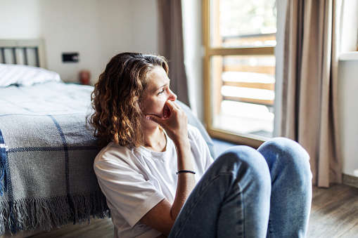 a woman sat at the end of her bed looking sad