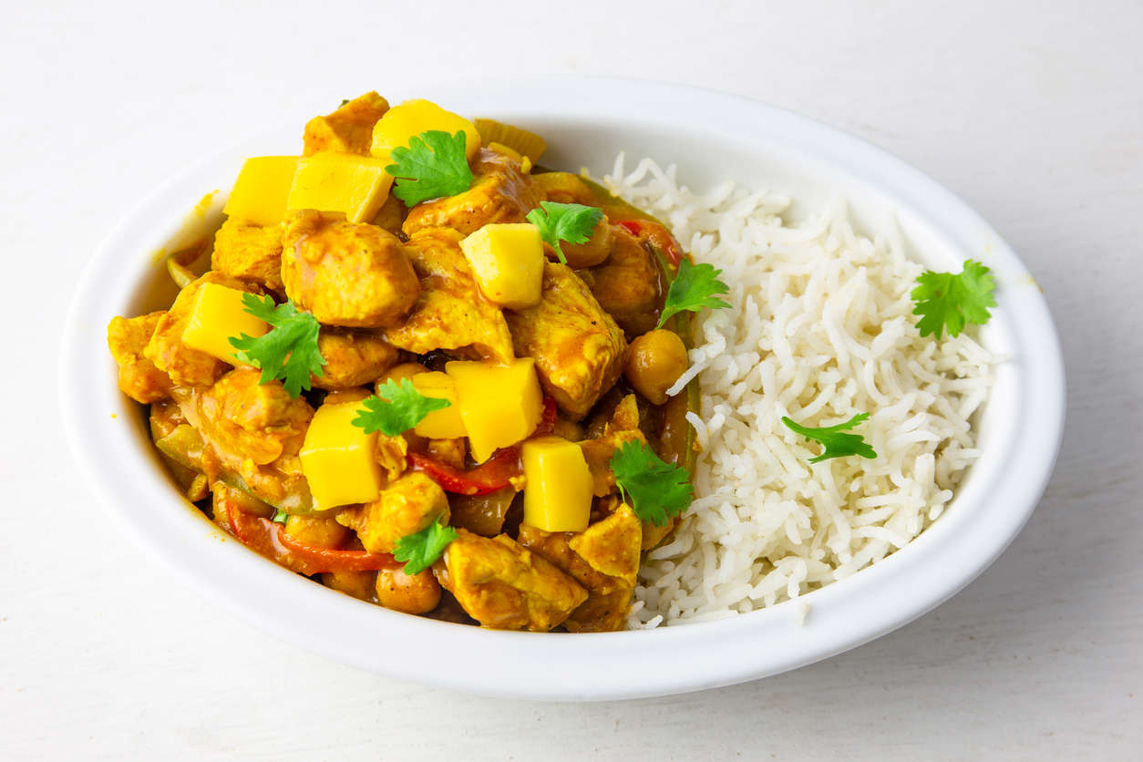 Vegan Sri Lankan curry and white rice in a white bowl with green herbs