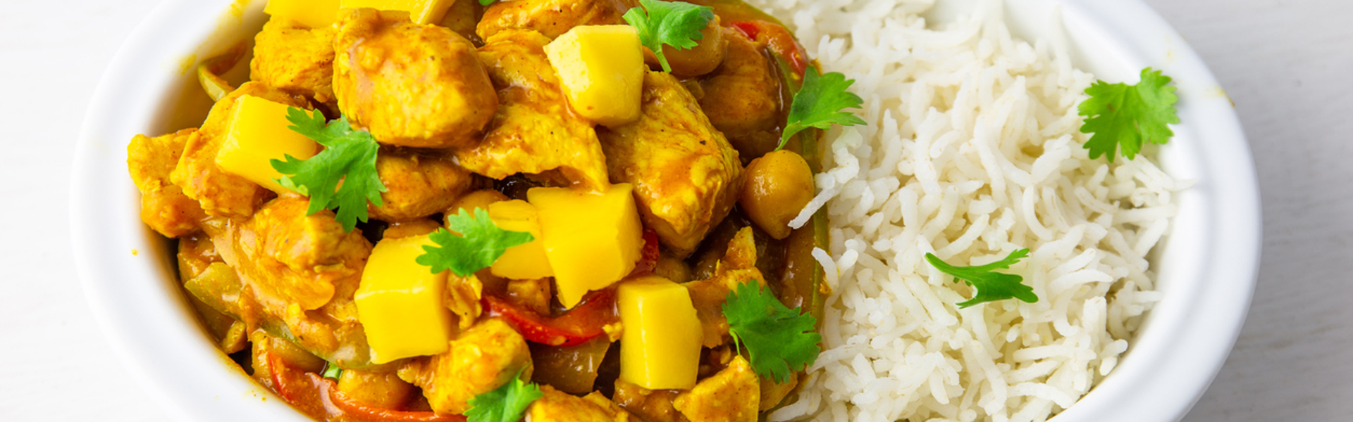 Vegan Sri Lankan curry and white rice in a white bowl with green herbs