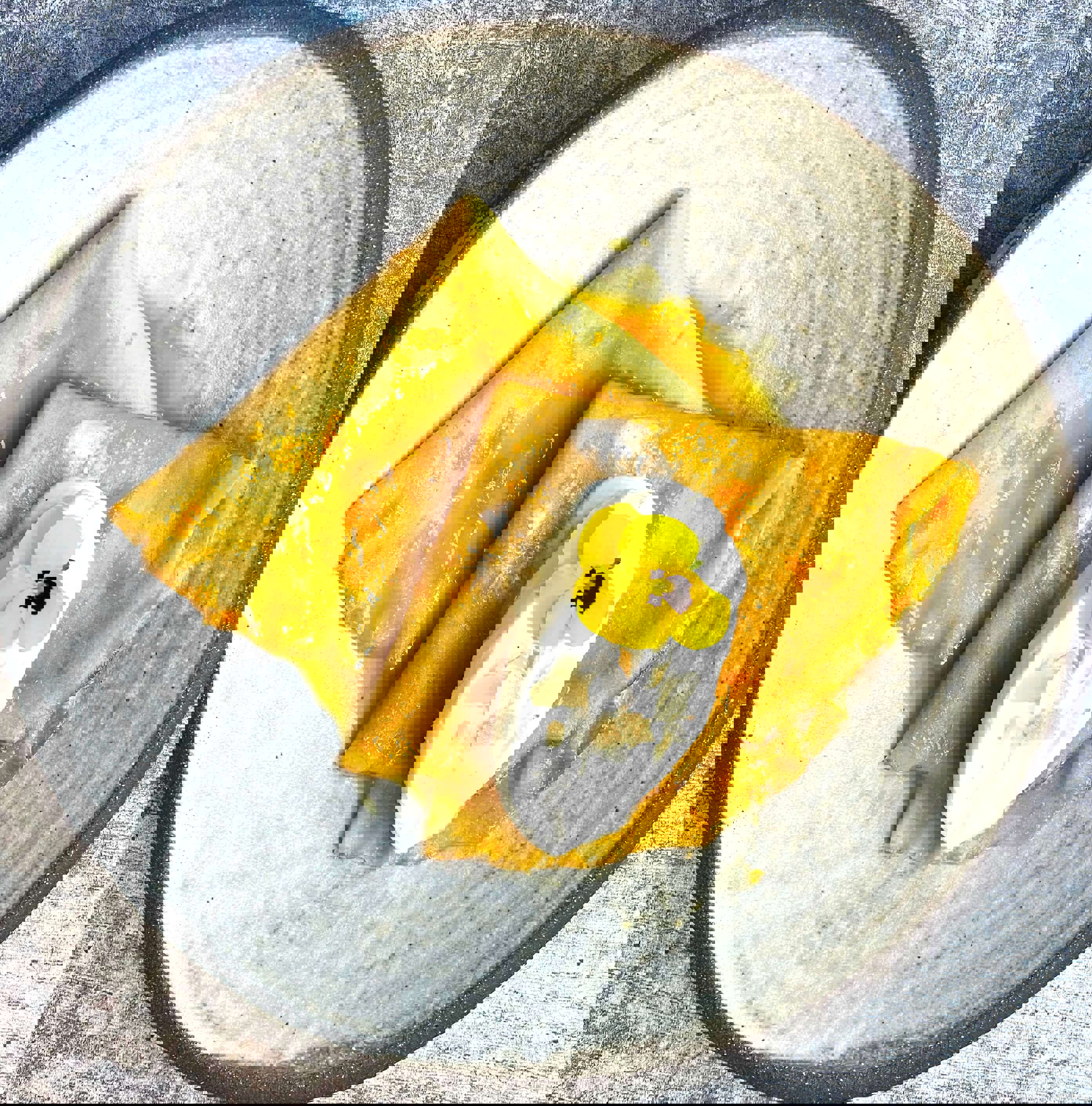 fresh homemade Crepes Suzette on a plate decorated with a scoop of white vanilla ice cream, maple syrup and a small yellow flower