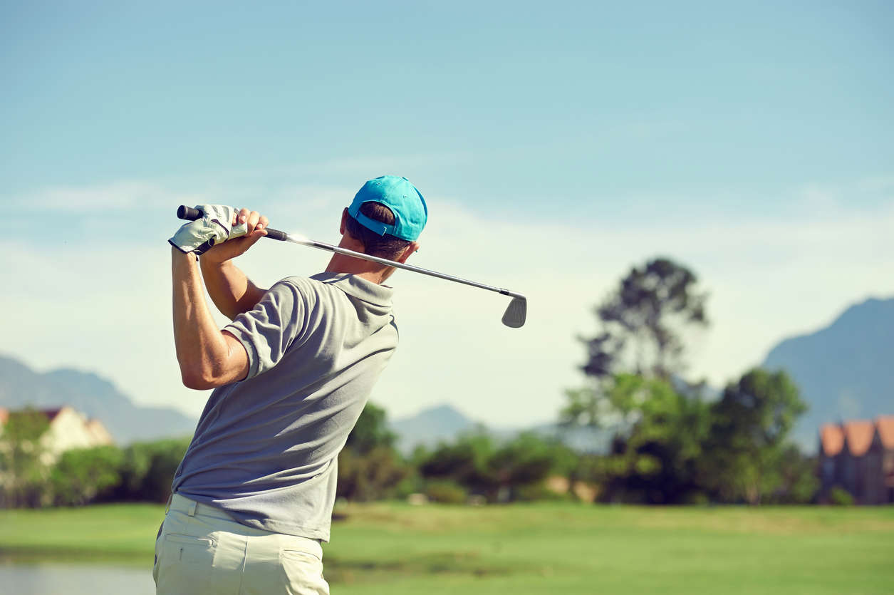 a picture of a man playing golf and completing a golf swing