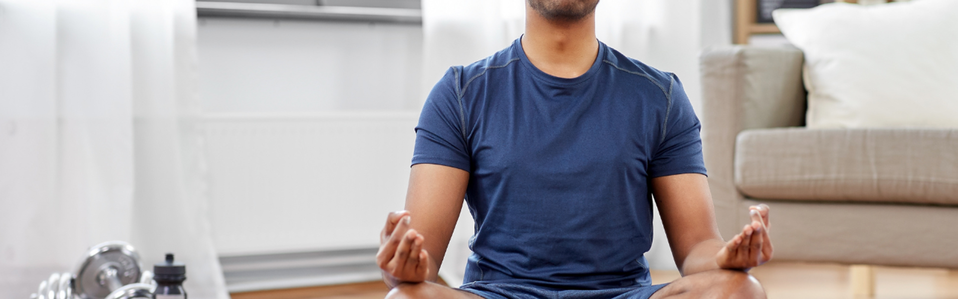 Main image: a man sat in lotus position, with eyes closed during a breathwork to calm and destress class. 