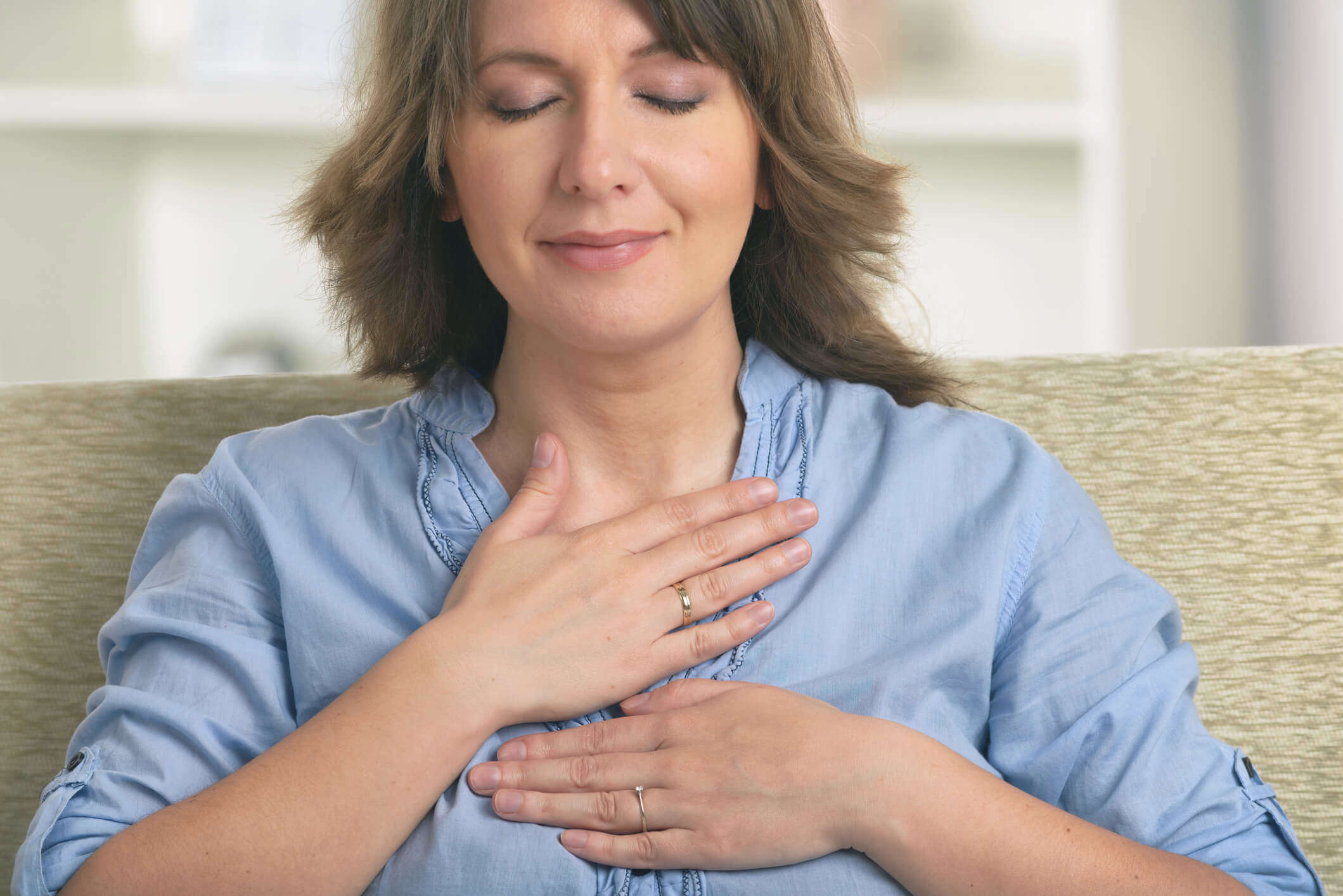 a woman with her eyes closed and hands on her chest