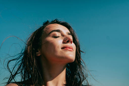 a woman with her eyes closed against a blue sky background