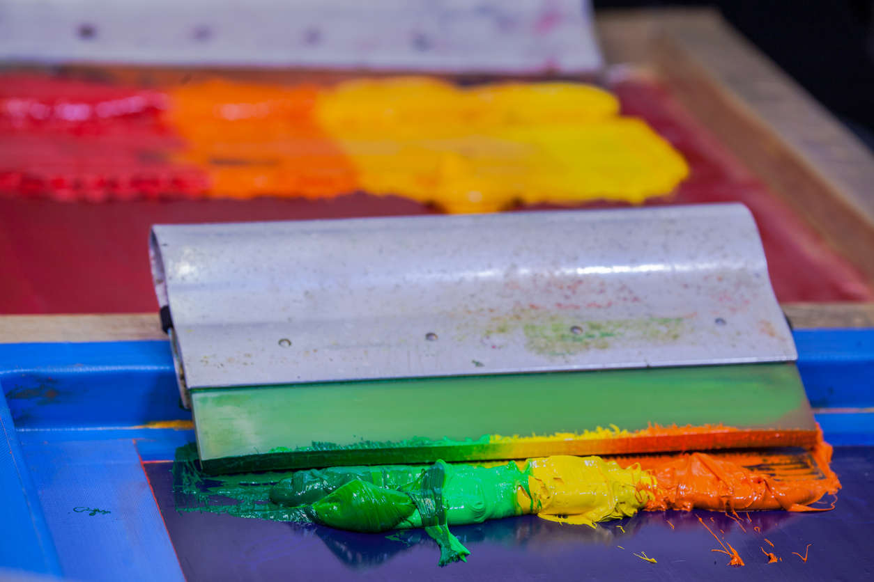 a screen printing tool with a rainbow of multi colour dye on a print press