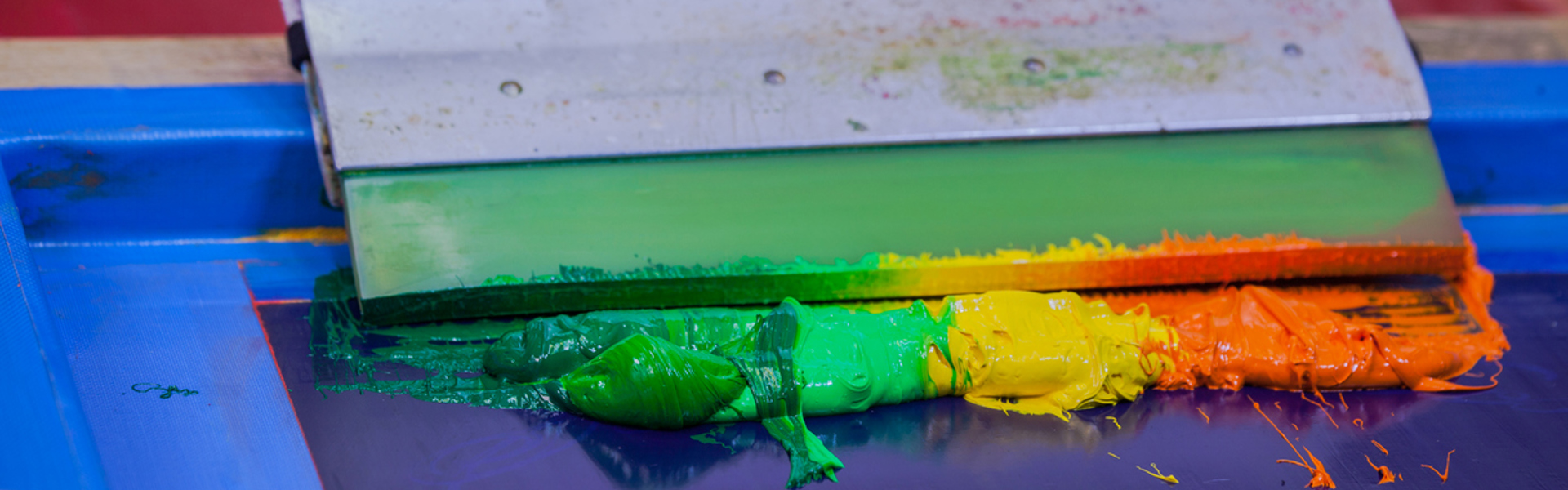 a screen printing tool with a rainbow of multi colour dye on a print press