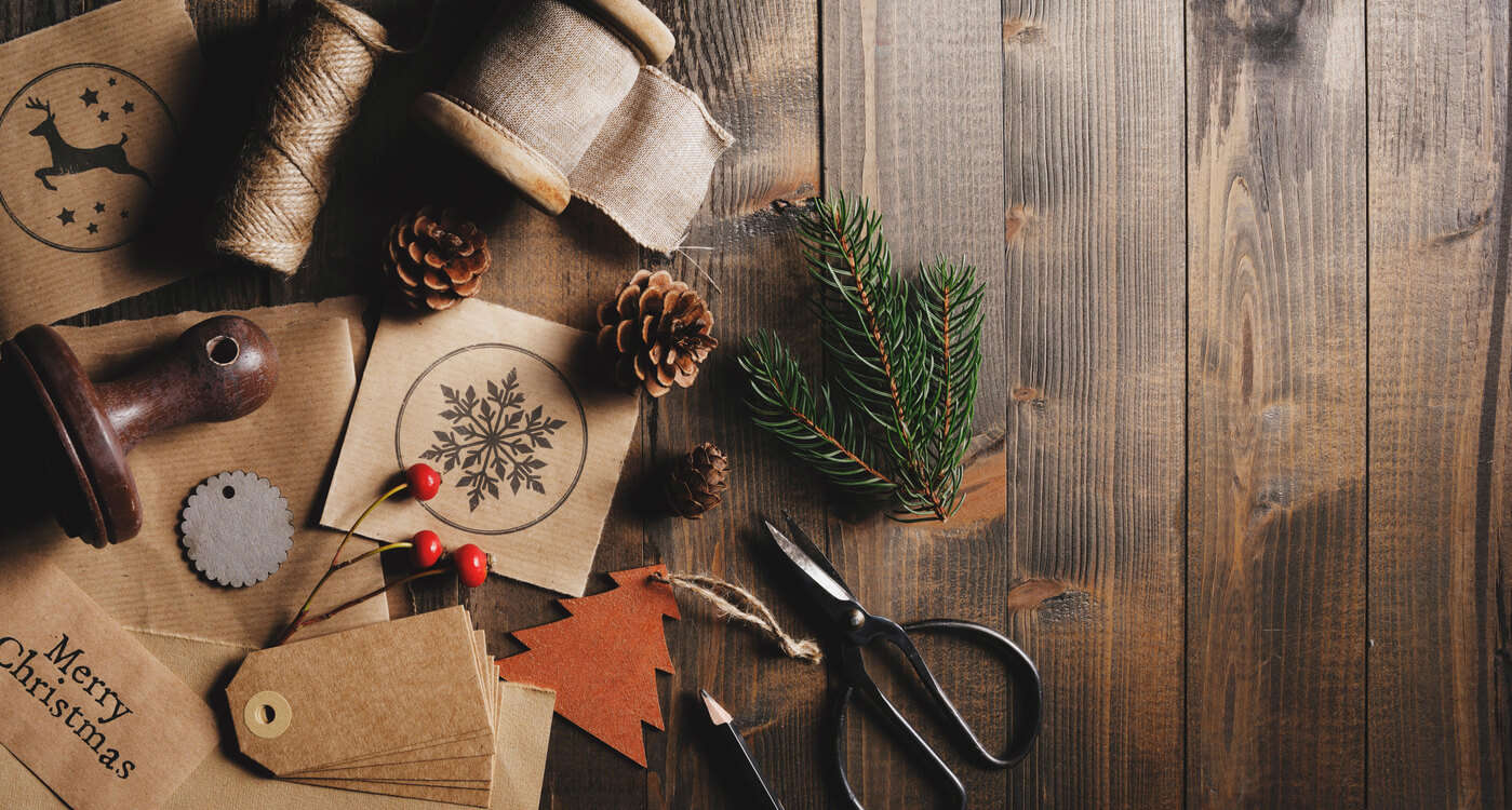 Seasonal foliage on a wooden table surrounded by craft tools 