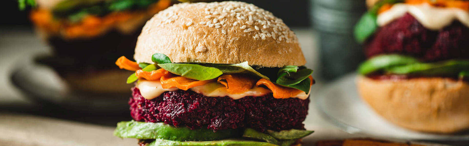 A beetroot burger with avocado and vegetables on a serving board with sweet potato fries