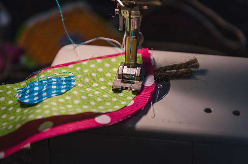 Main image: using a sewing machine to sew pieces of scrap fabric together to make a fabric gift bag.