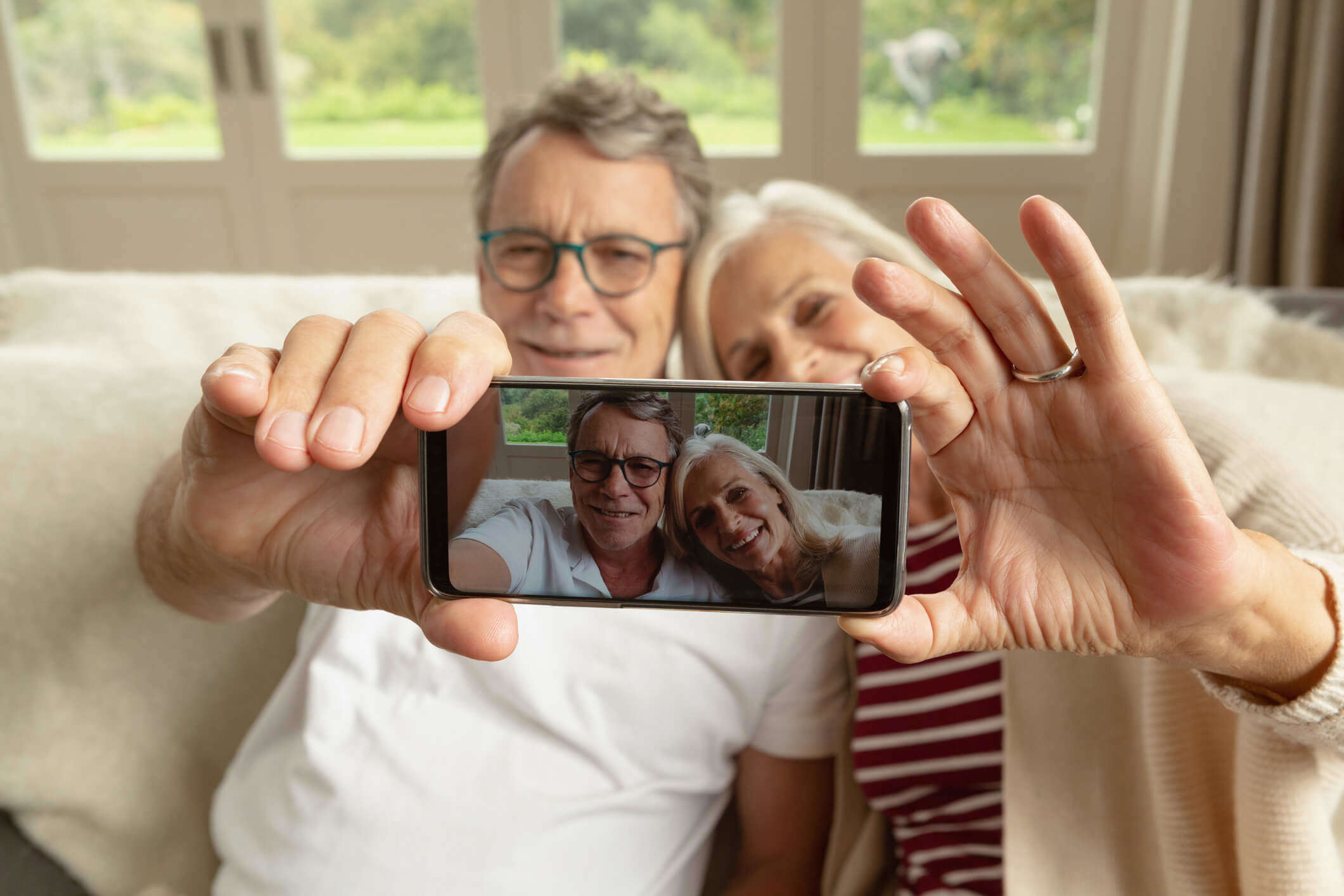 an older couple sat on a sofa taking a selfie