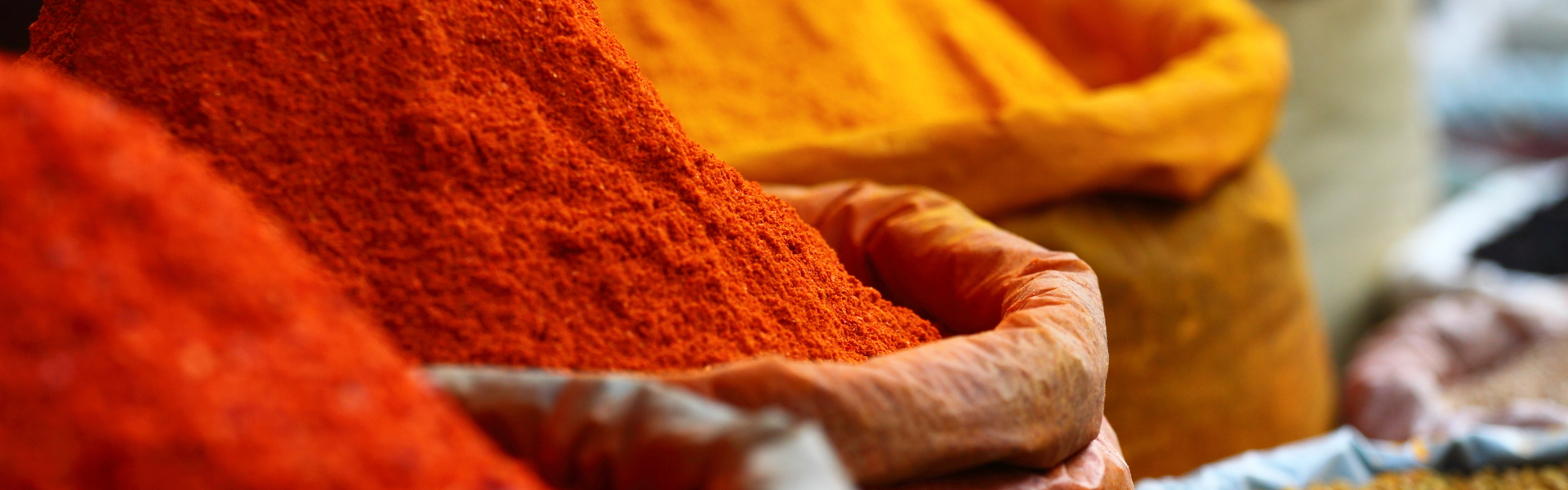 Main Image: Sacks of red, orange and yellow spices.