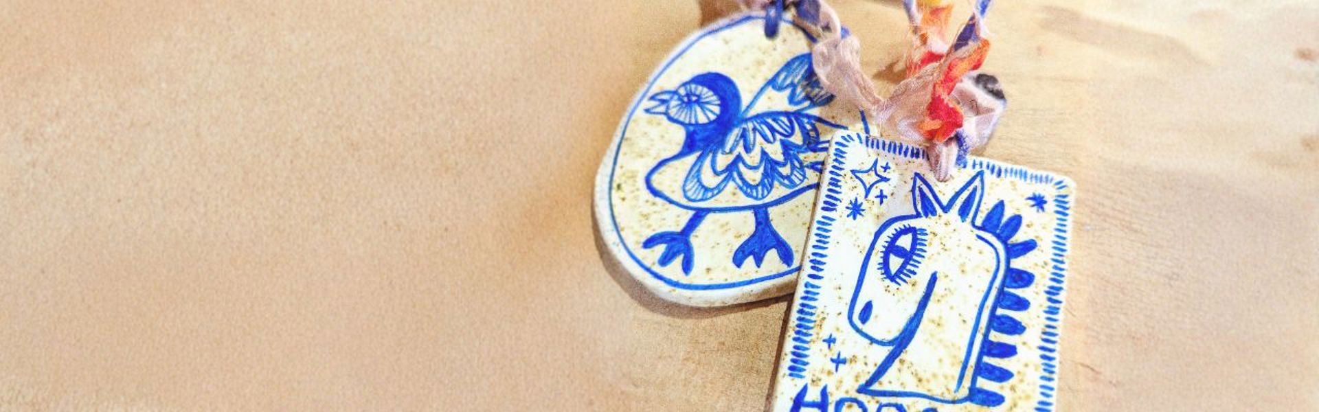 Main image: handmade air dry clay decorations, with a textured clay using teabags. Painted with blue designs of a bird and a horse. 