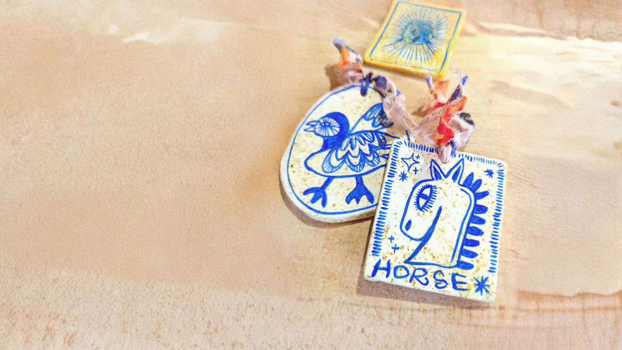 Main image: handmade air dry clay decorations, with a textured clay using teabags. Painted with blue designs of a bird and a horse. 