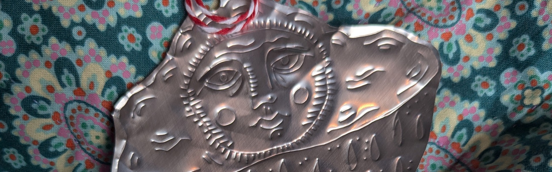 Recycled Tin Decorations with white and red striped string, on a pattered background