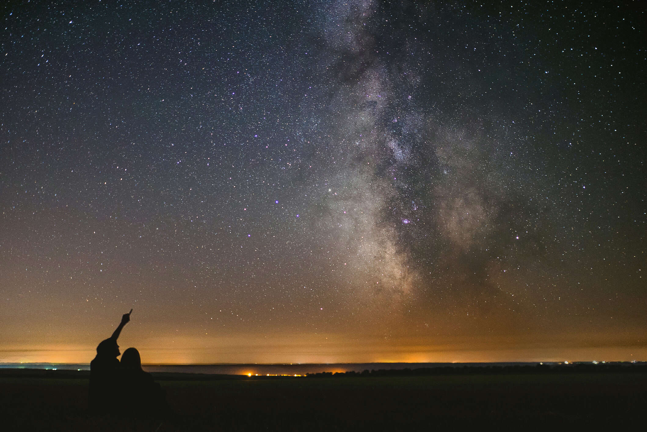 a silhouette of two people stargazing