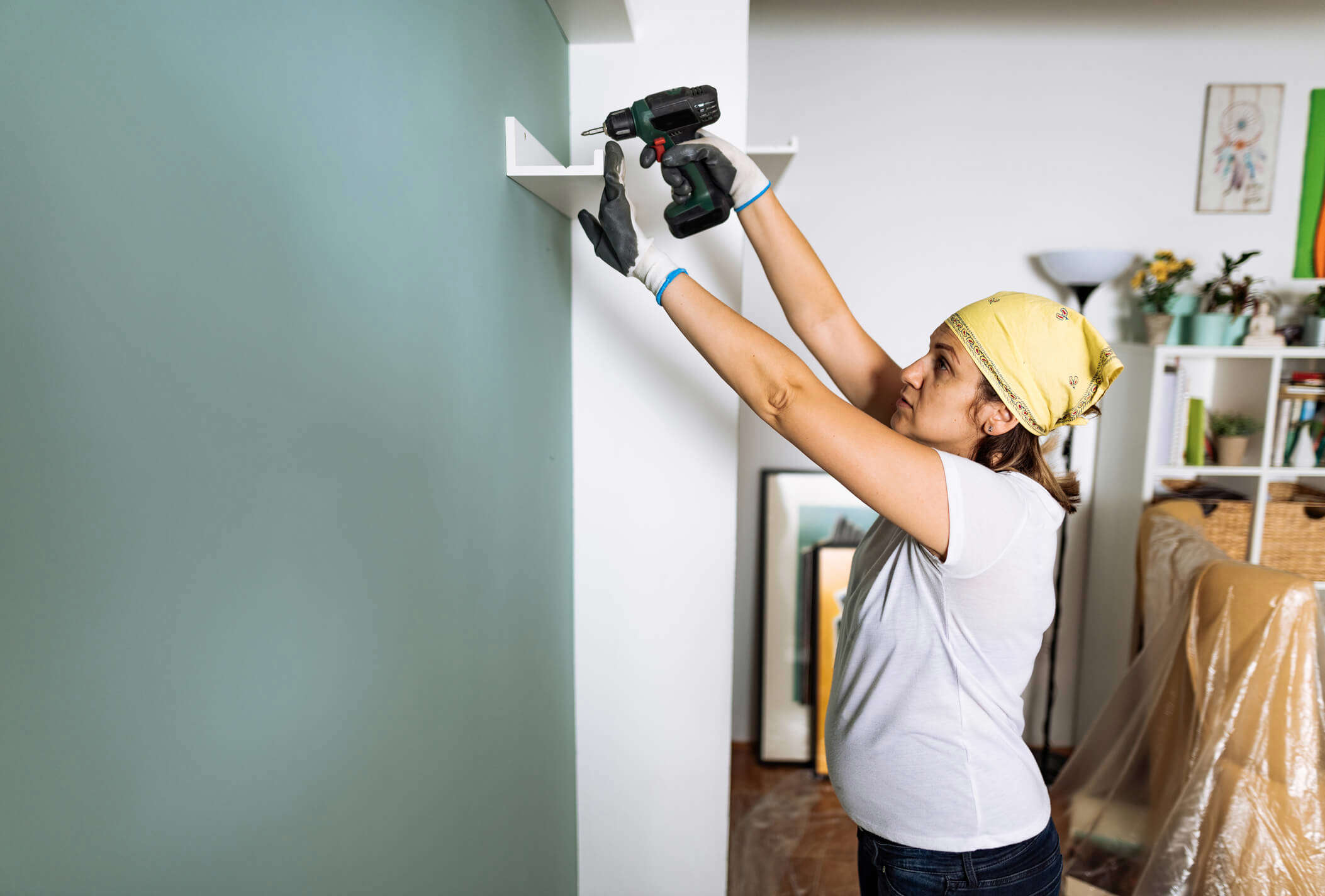 a woman putting up a DIY shelf at home using a drill