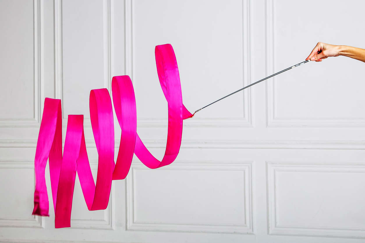 a pink rhythmic gymnastics ribbon against a white wall