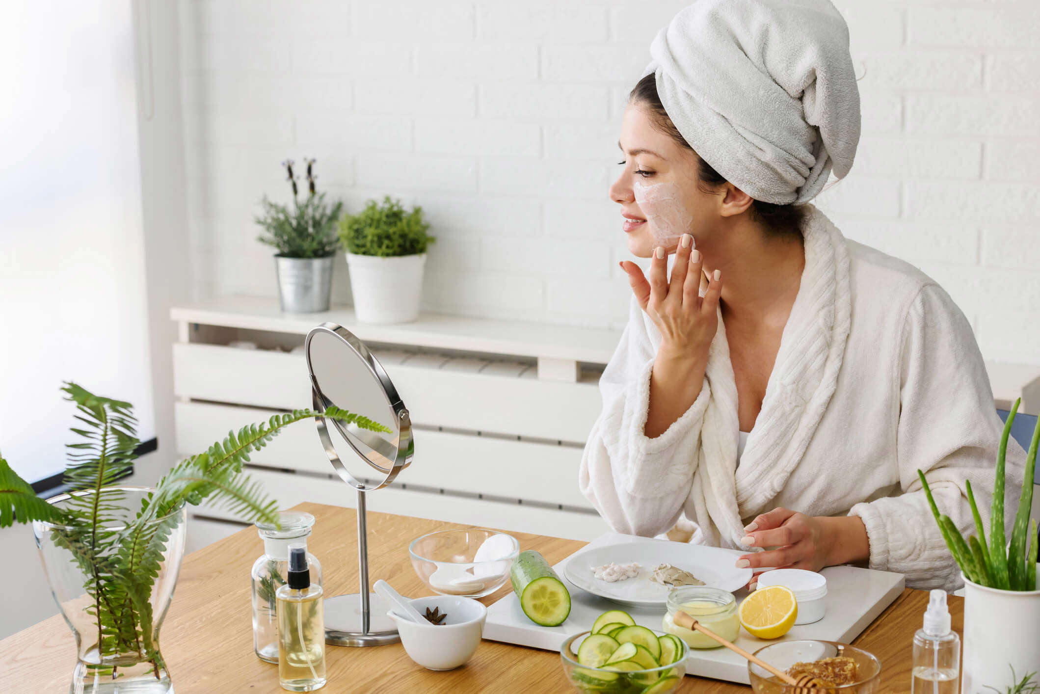 a woman in a robe putting a homemade face mask on