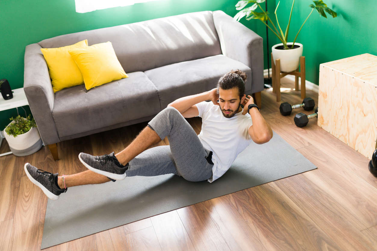 a man completing a HIIT workout at home on a grey yoga matt