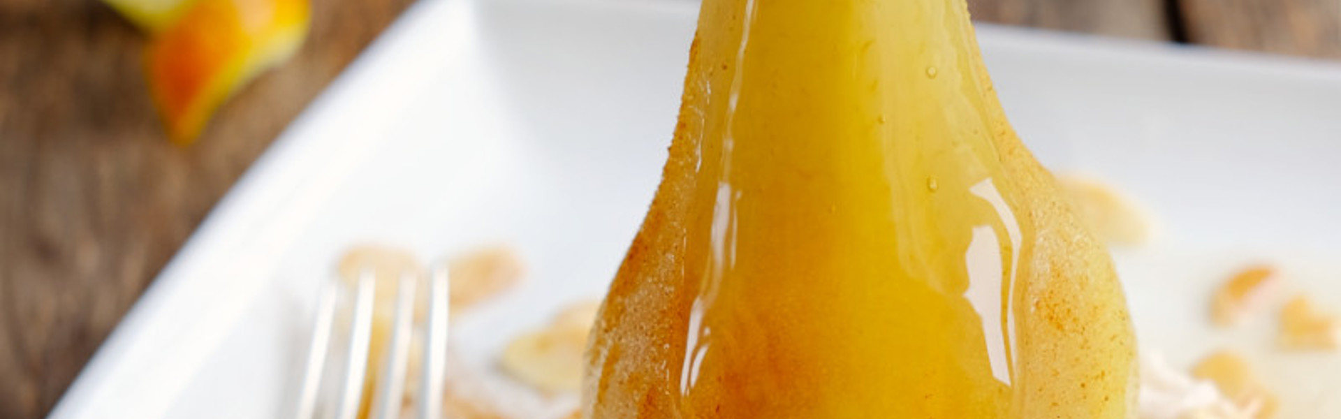 Main image: a vegan Christmas recipe idea - a poached pear on top of maple soft cheese, with a drizzle of maple sauce. 