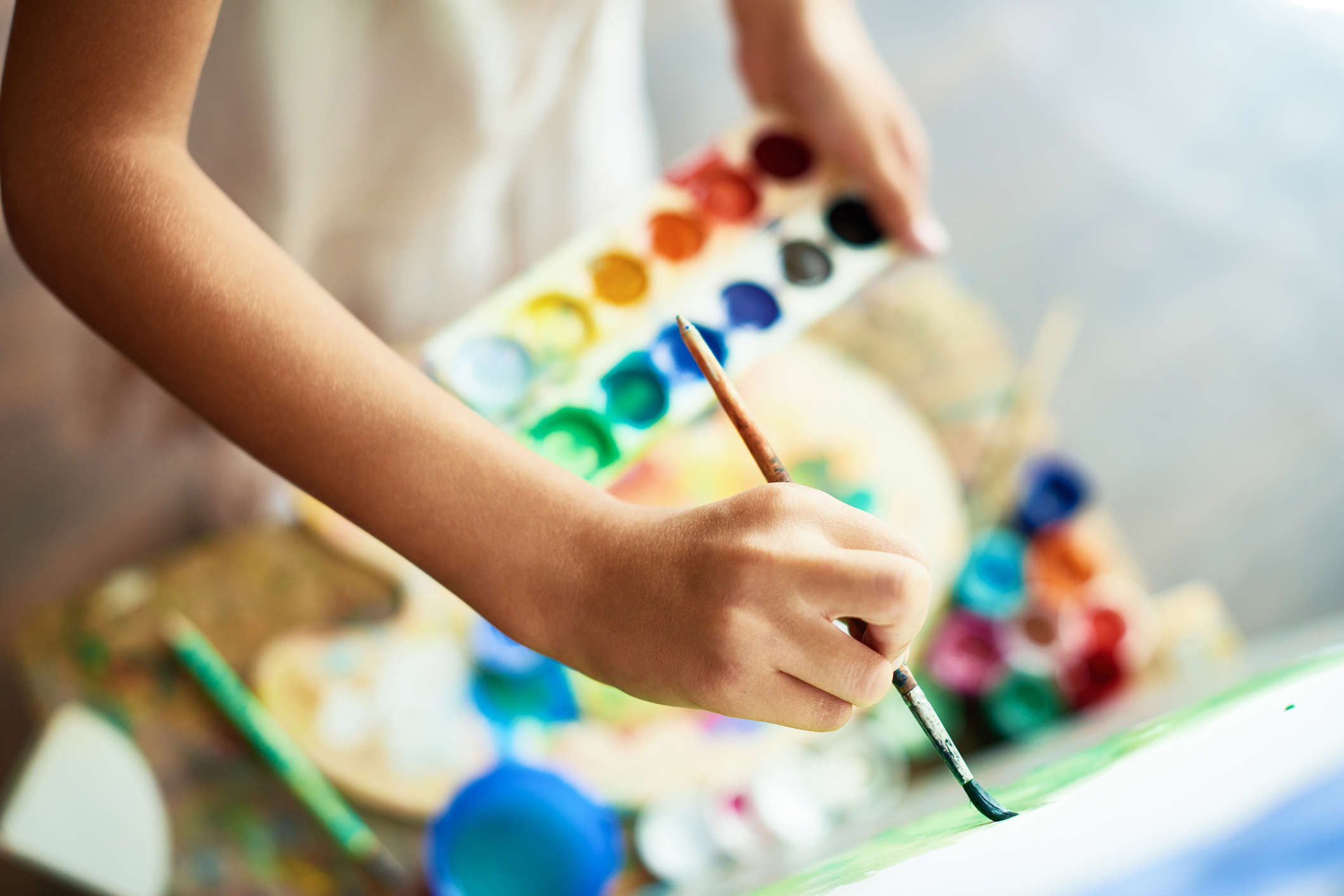 a person holding a paint pallet with multi colours and painting on a canvas