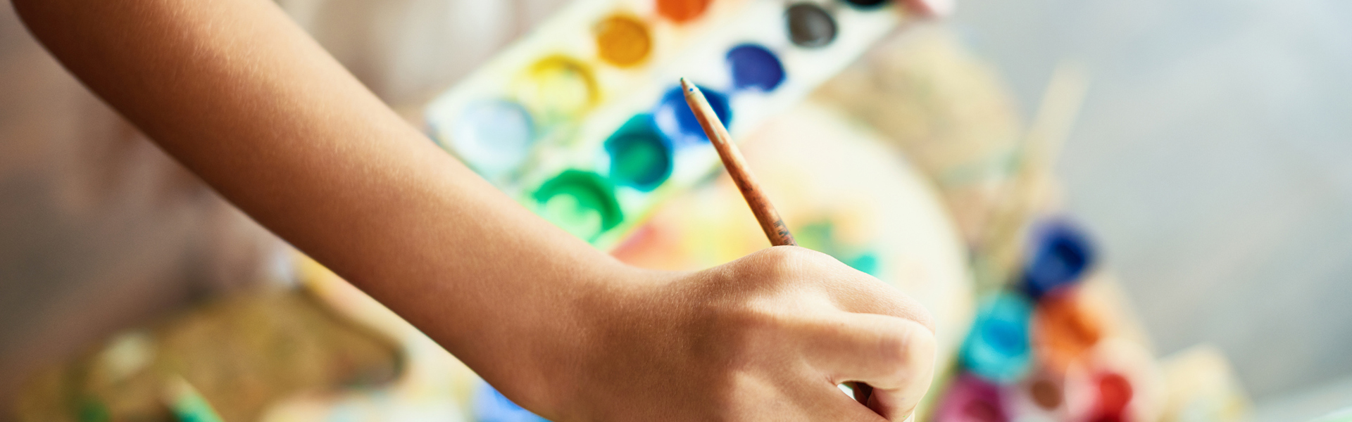 a person holding a paint pallet with multi colours and painting on a canvas