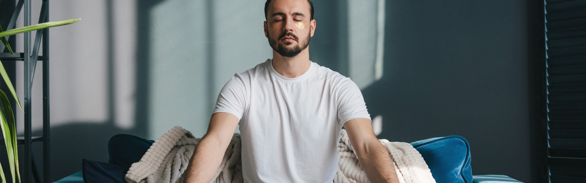 a man sat cross legged on a sofa at home meditating