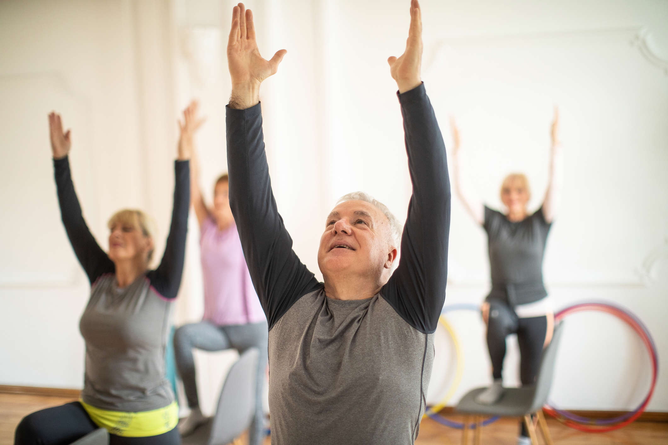 group of 4 people on chairs stretching upwards with both arms