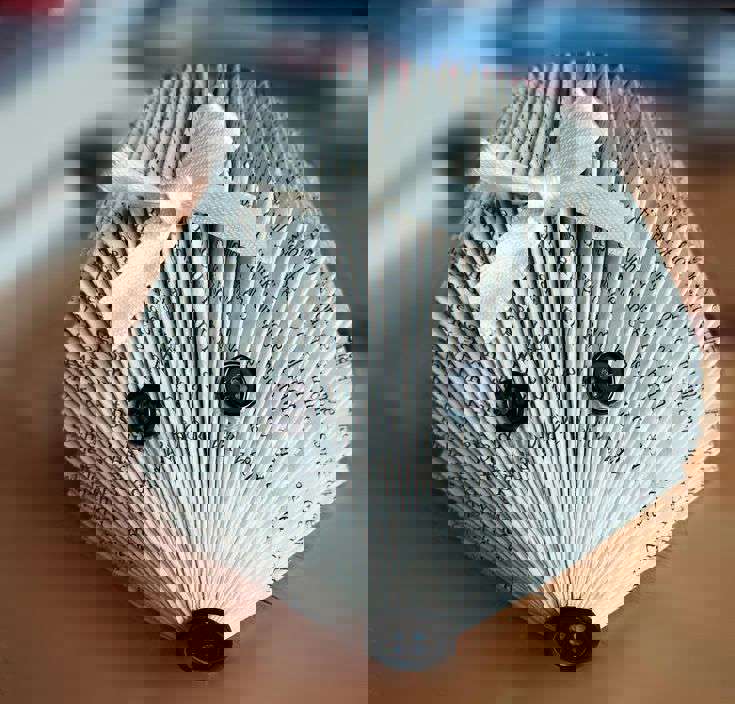 Main image: a paperback book turned into a cute hedgehog using book folding techniques and buttons as the eyes and nose, with a little ribbon accessory on the head.