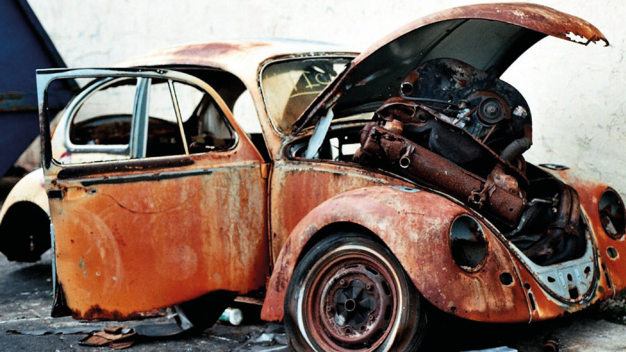 a picture of an old VW beetle with it's hood up reciveing an MOT