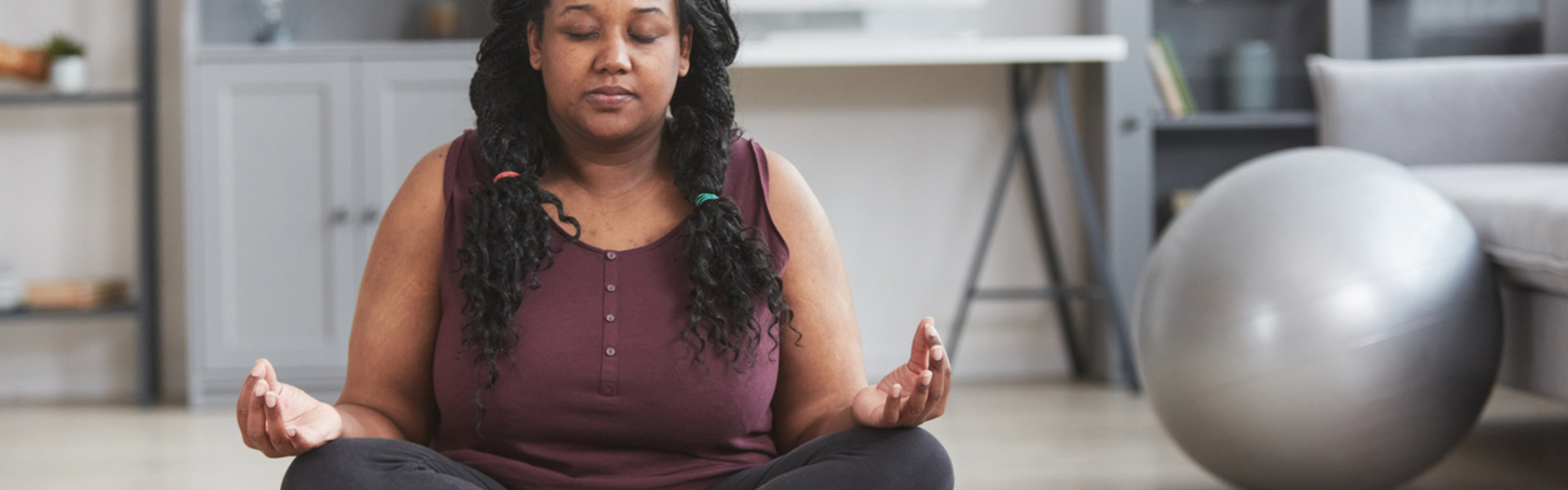 a woman sat cross legged with eyes closed in the living room meditating at home