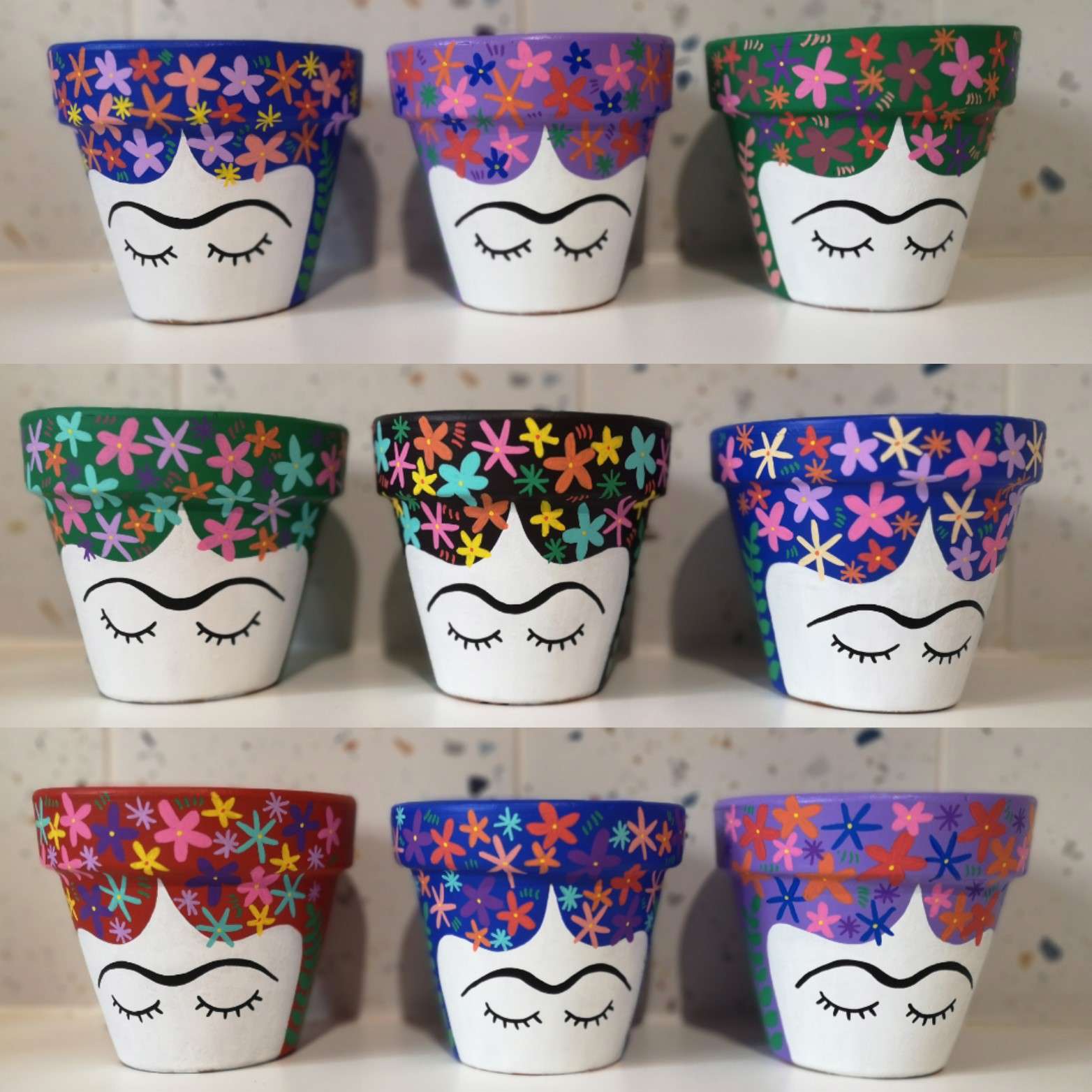 Painted ceramic plant pots in a variety of colours depicting a painted image of Frida Kahlo's face with eyes closed