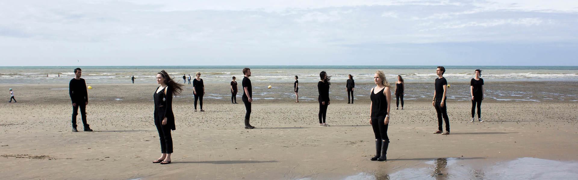 the London Contemporary Voices choir stood spaced out on a beach wearing black clothes