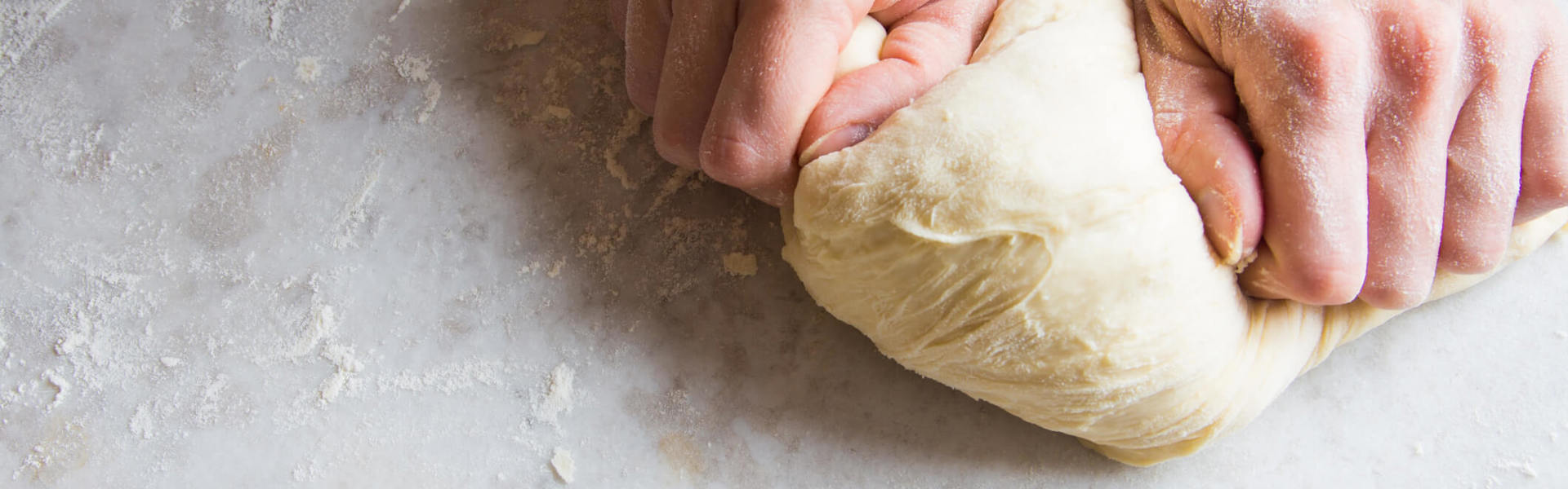 fresh bread dough being rolled out on a clear surface