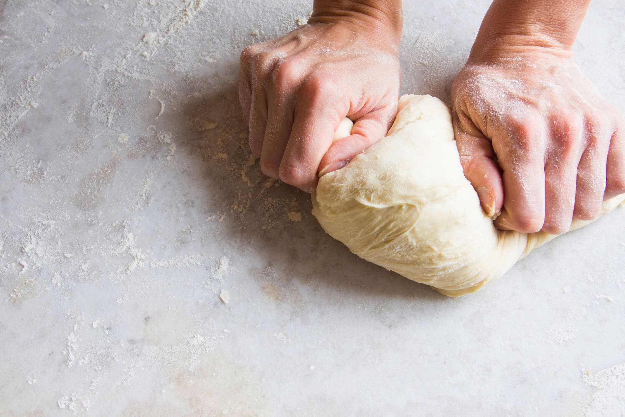 fresh bread dough being rolled out on a clear surface