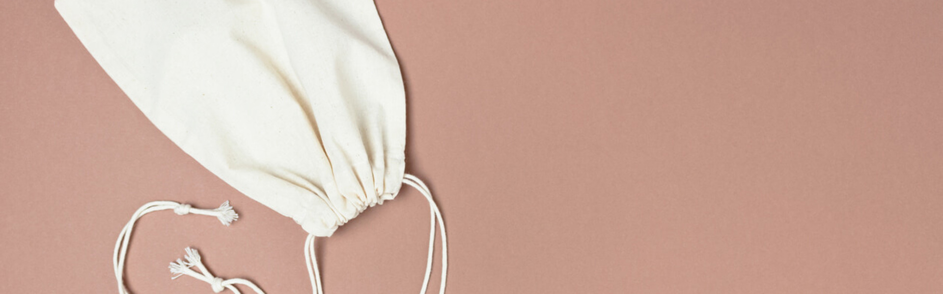 two cream canvas drawstring bags on a brown background