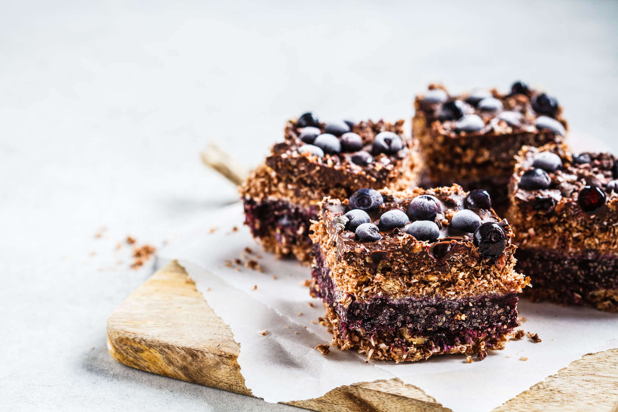 Vegan dessert squares on a white plate topped with blueberries