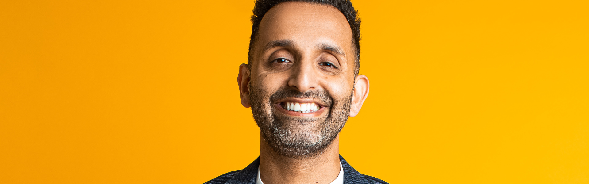 Main Image: a photo of Dr Amir Khan, smiling with a yellow background.
