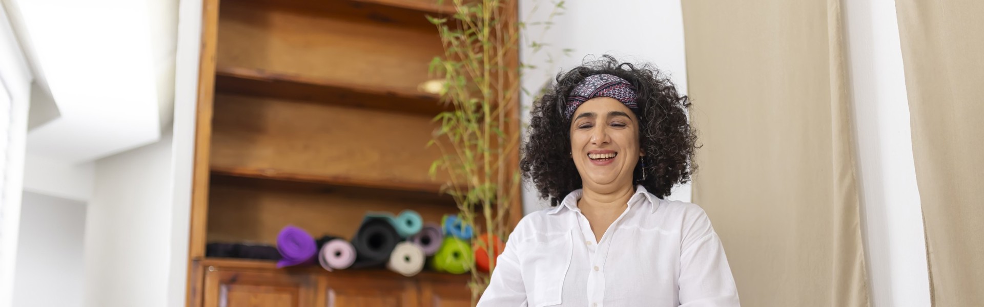 Main image: woman sat at home, taking part in an online meditation or yoga class as part of Mindspace Week!