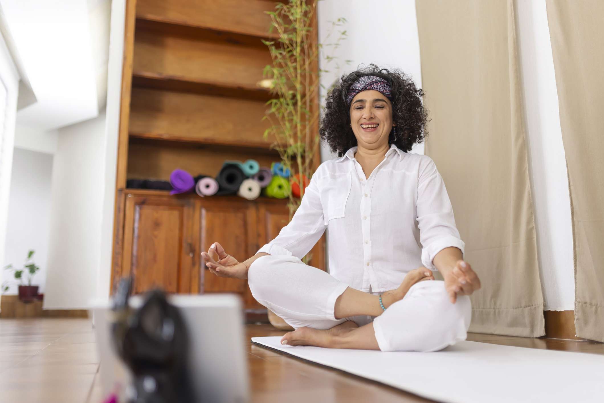 Main image: woman sat at home, taking part in an online meditation or yoga class as part of Mindspace Week!