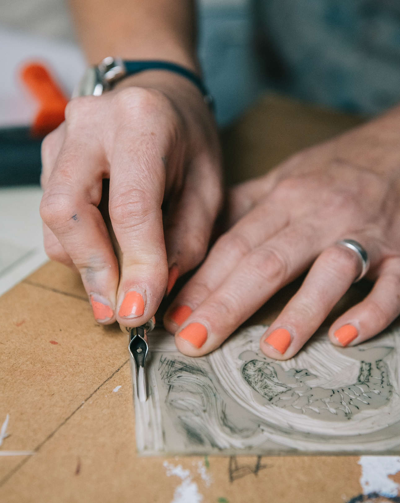a close up of hands lino cutting a snowscene